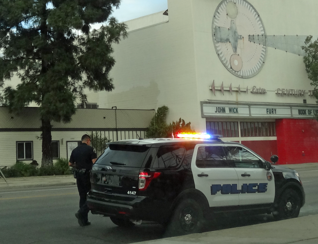 LA COP NEXT TO POLICE CAR WITH FLASHING LIGHTS SIRENS